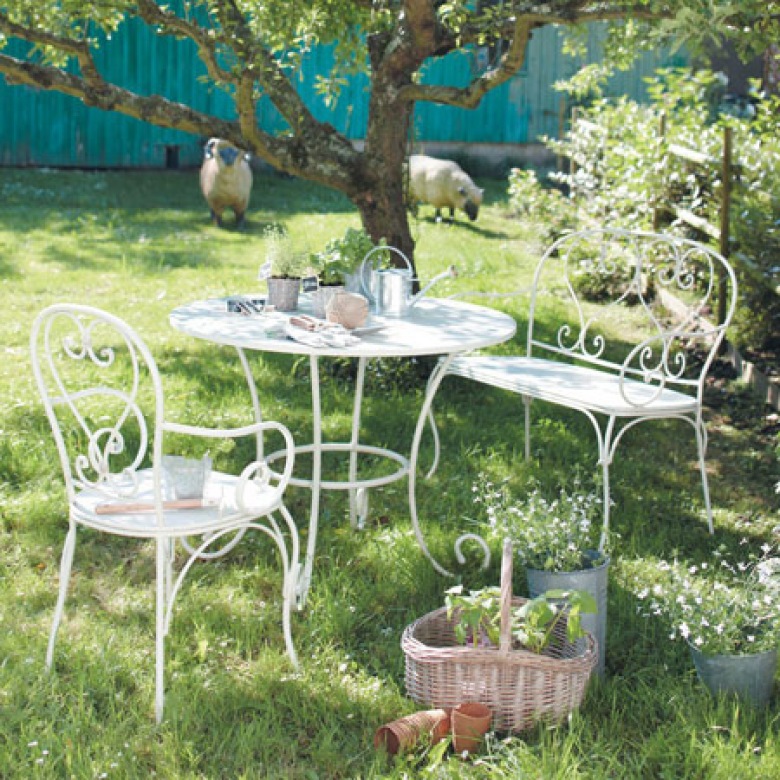 Białe kute meble ogrodowe w deserowej aranżacji w letnim ogrodzie (23932)
