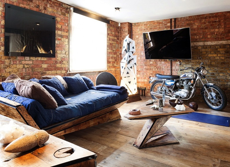 Motocykl Harley,dizajnerski stolik kawowy z drewna,oryginalana sofa z bszafirowymi poduchami i ściany z czerwonej cegły (23697)