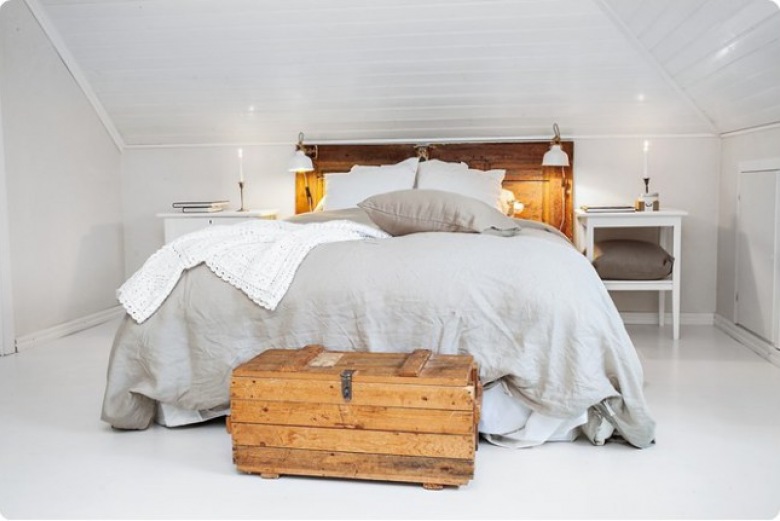 Biała sypialnia na poddaszu z drewnianym łóżkiem, drewnianym miodowym kufrem skrzynią i szarą lnianą pościelą (27876)