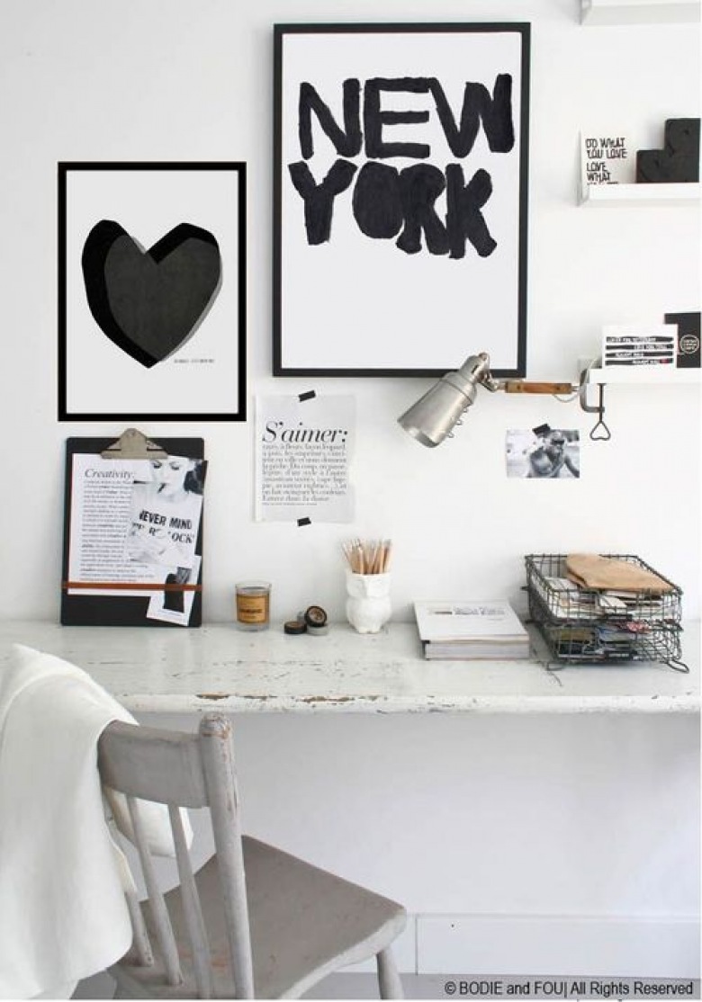 Białe biurko i białe krzesło postarzane w stylu schabby,druciany pojemnik na dokumenty,biało-czarne plakaty i typografie na białej ścianie nad biurkiem (26138)