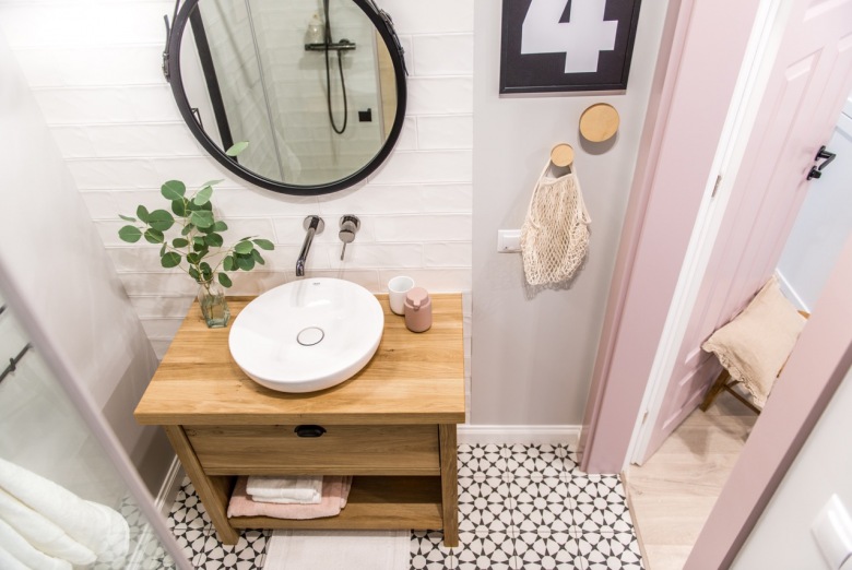 Mała łazienka jest nie tylko urządzona funkcjonalnie, ale też estetycznie. Różowe drzwi pasują do delikatnego wystroju, a czarne elementy ożywiają...