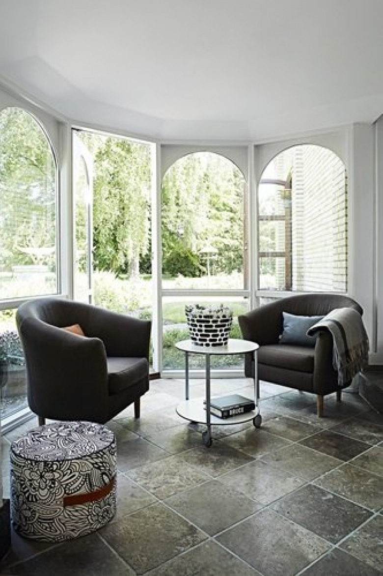 Szara kamienna płytka na podłodze,nowoczesne szare fotele,okragły stolik na kółkach w salonie z łukowanymi oknami w wykuszu (25039)
