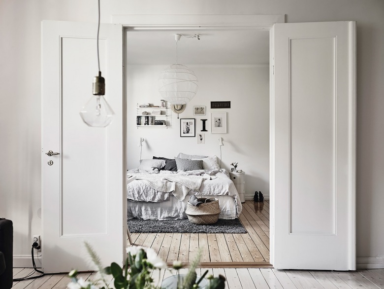 Bielone deski na podłodze,nowoczesne grafiki na białej ścianie i białe drewniane dwuskrzydłowe drzwi w sypialni (47740)
