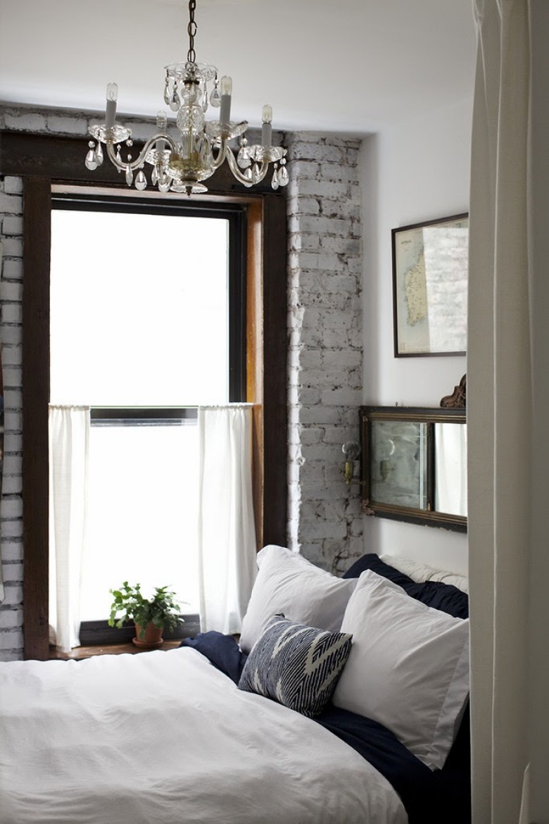 Biała cegła, kryształowy żyrandol i ciemne drewniany ramy okien w sypialni (22968)