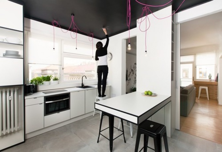 Białe meble , różowe kable z żarówkami i czarny sufit i ściany nad szafkami kuchennymi (22281)