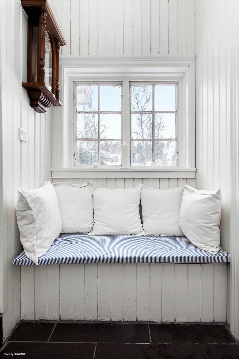 Pomysłowe  siedzisko z białych desek i poduszek pod małym oknem (21961)