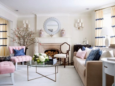 Różowe pikowane fotele,białe zasłony w niebieskie pasy,okrągłe lustro nad kominkiem i szklany metalowy stolik w eklektycznym salonie (28319)