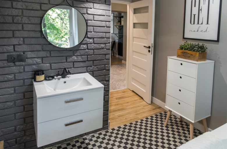 Dobrane kolory bieli, szarości i czerni dodają łazience eleganckiego charakteru. Jednym z ciekawszych rozwiązań jest podłoga z geometrycznym...