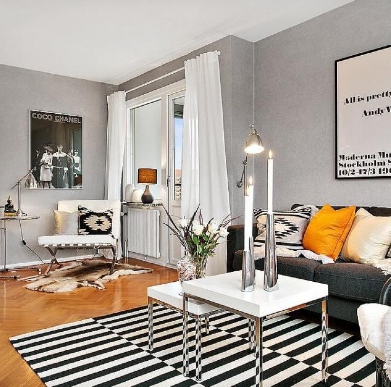 Szare ściany,białe stoliki nowoczesne ,biało-czarny dywan w paski i żółte poduszki na szarej sofie w salonie skandynawskim (27513)