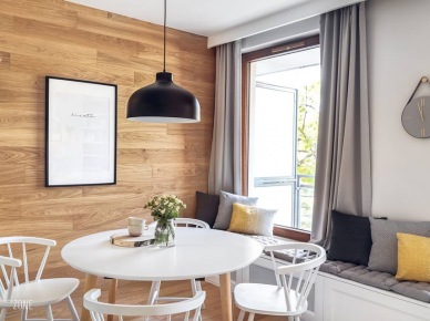 Inspirująca aranżacja mieszkania z białą kuchnią i drewnianą ścianą w jadalni!