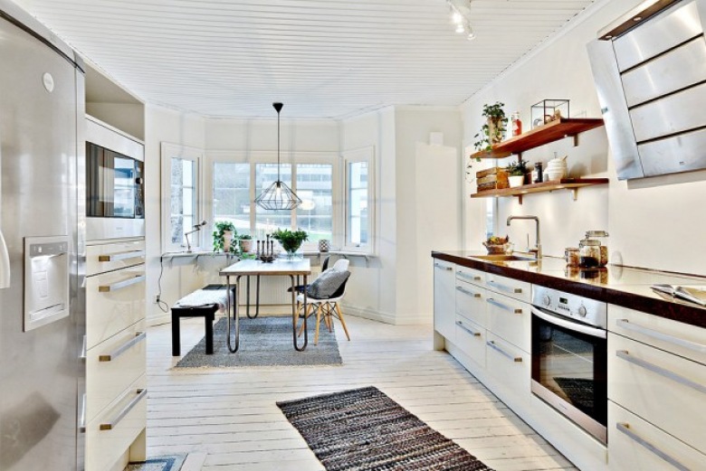 Skandynawska biała kuchnia z czarnymi blatami,bielonymi deskami na podłodze i metalowym stołem z drewnianym blatem (27699)