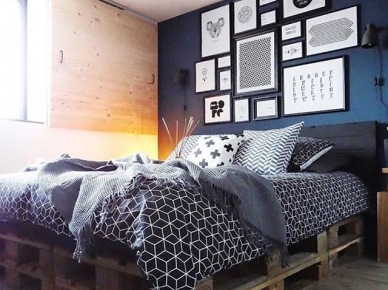 Łóżko z palet i galeria grafik na granatowej ścianie w sypialni (54201)