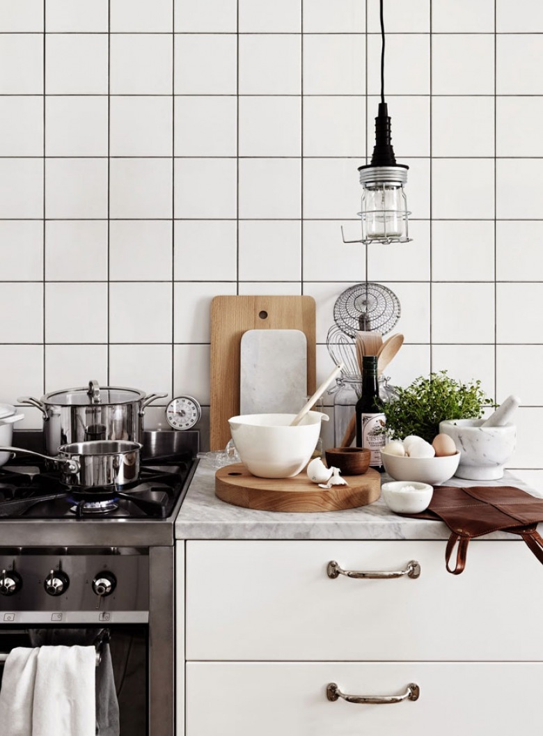 Biała kwadratowa glazura na ścianie w kuchni,industrialna lampa wisząca,drewniane deski deserowe w białej kuchni (26471)