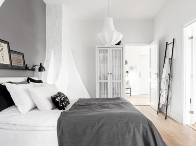 Szara narzuta na łóżku,biała szafa witryna,czarna drabina dekoracyjna w roli wieszaka w biało-szarej sypialni (48031)