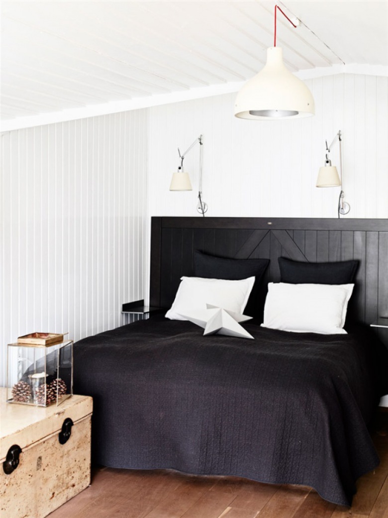 Czarne drewniane łóżko,czarna narzuta,drewniana skrzynia vintage i białe lampy i kinkiety w białej sypialni (27693)