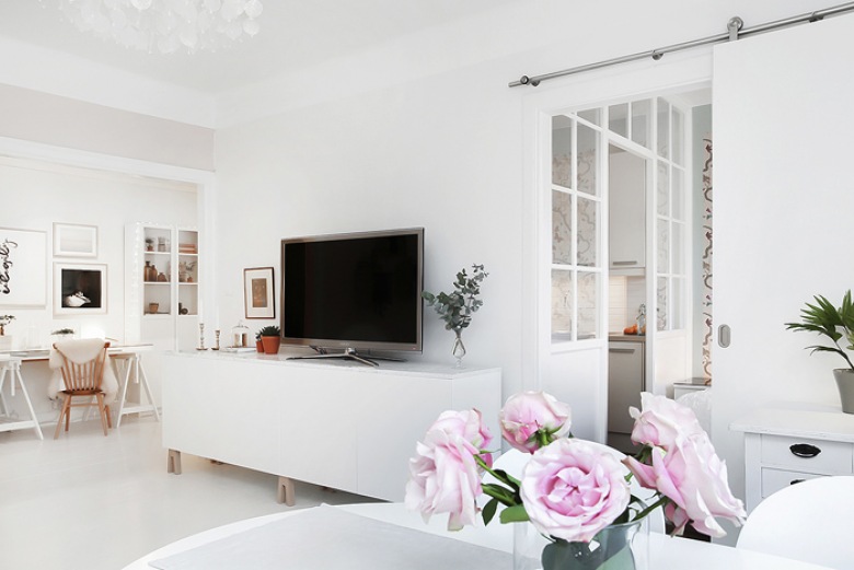 Przesuwne białe drzwi w salonie skandynawskim z kącikiem tv i biurkiem (27860)