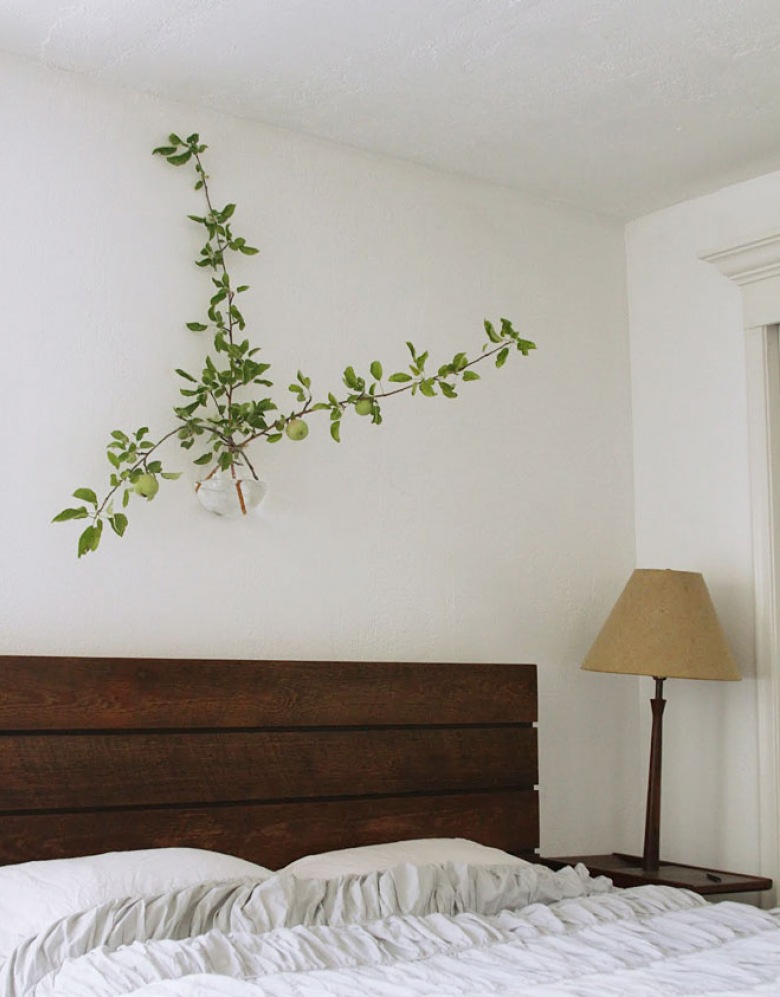 Wiszący wazon z zieloną rośliną nad łóżkiem z drewnianym wezgłowiem z desek (20898)