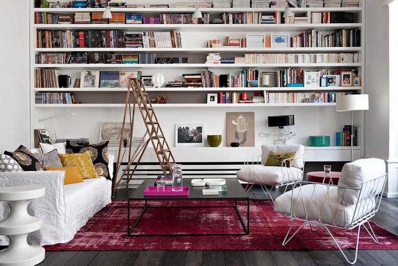 Nowoczesna aranżacja salonu z bialymi półkami na ścianie,drabiną,nowoczesnymi metalowymi fotelami w bieli i różowym dywanem vintage (26181)