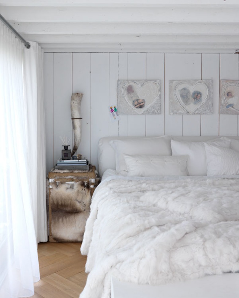 Dekoracyjne serca w białej sypialni z futrzaną narzutą, drewnianą podłogą i szafką kufrem w beżowo-białym futerku (27682)
