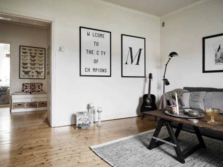 Plakaty, typografie,drewniana ława szara ze szklanym blatem i szara sofa z szarym dywanem w salonie (26556)