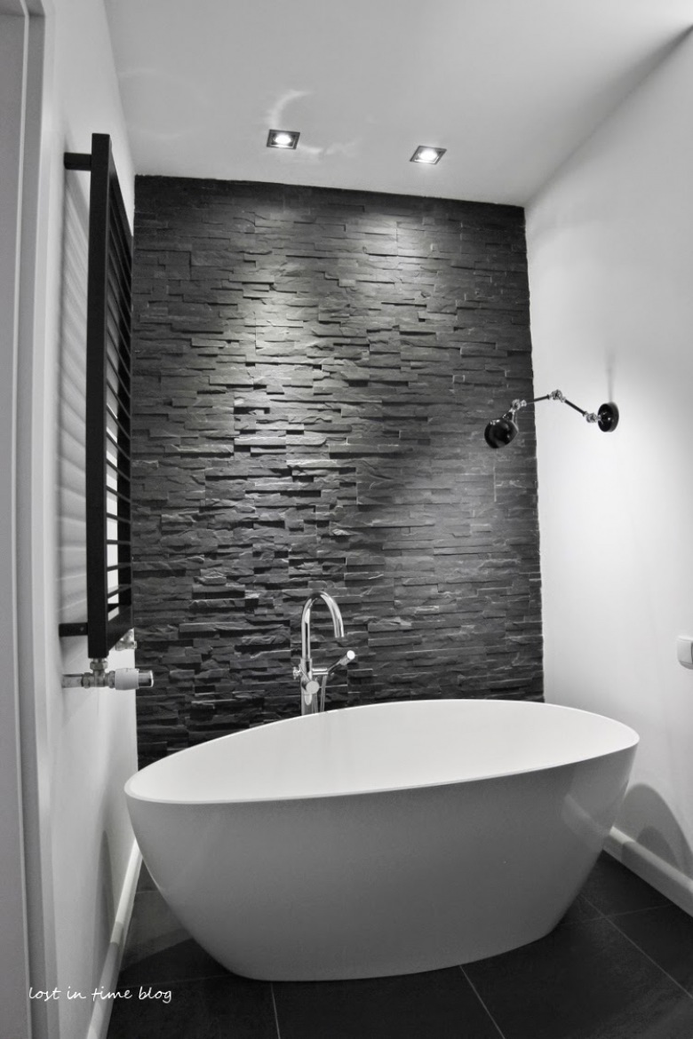 Czarny kamień łupek na scianie w łazience,biała owalna wanna wolnostojąca,czarny kinkiet nad wanną (26015)