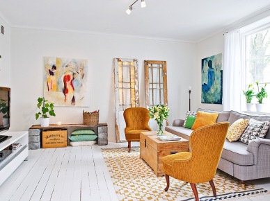 Ciemnożółte fotele i poduszki,drewniane skrzynki,nowoczesne obrazy i skandynawski dywan w aranżacji salonu (24546)