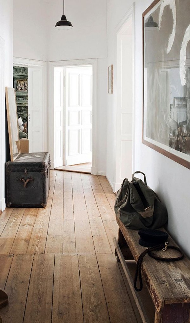 Czarny kufer kolonialny,drewniana wiejska ławka,drewniane deski na podłodze  i duża czarno-biała fotografia na białej ścianie w przedpokoju (26067)