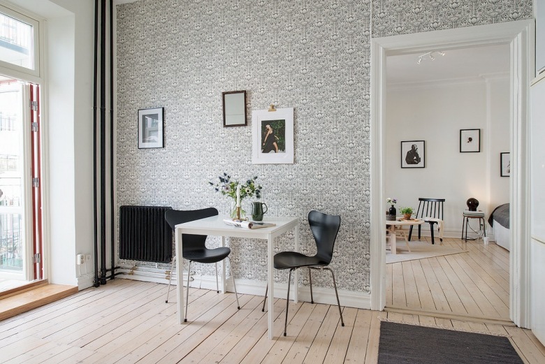 Biały stół z czarnymi krzesłami przy ścianie z czarno-białą tapetą (22616)