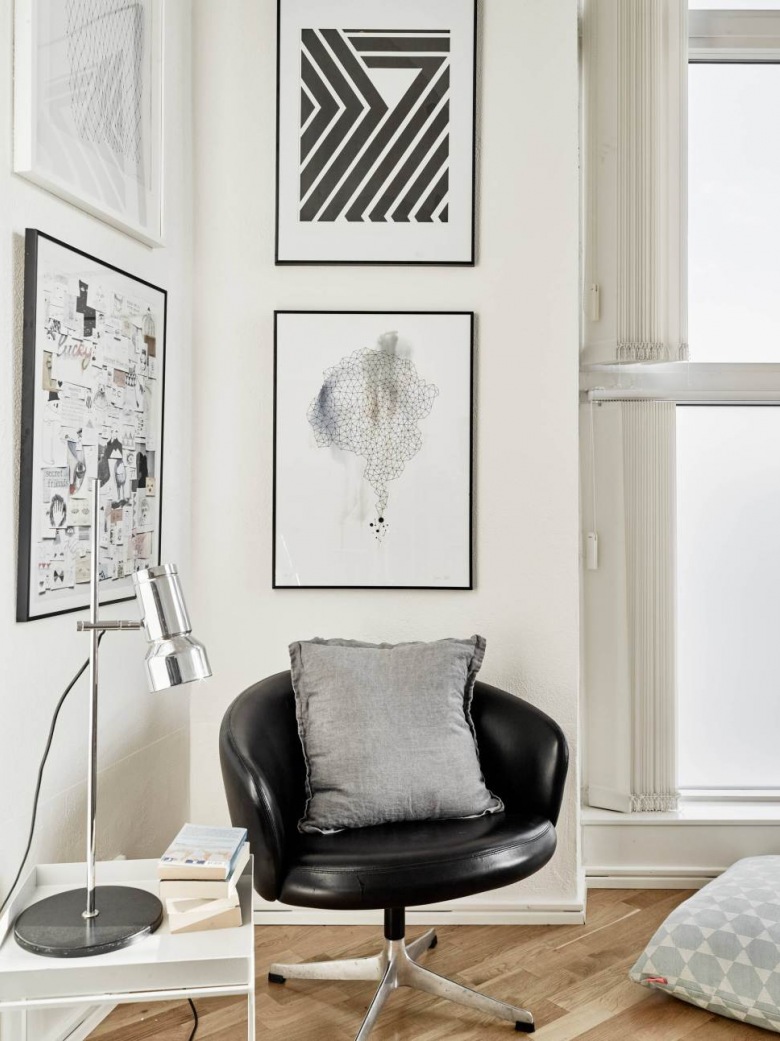 Nowoczesne biało-czarne grafiki,czarny skórzany fotel ,srebrna lampa biurkowa i biały stolik z tacą (26860)