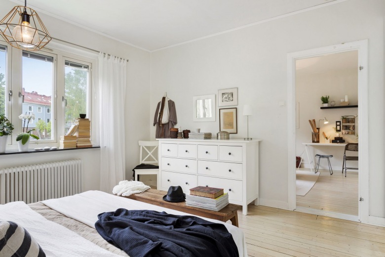 Biała  komoda z szufladami, druciana lampa i drewniana ławka z naturalnego drewna w dekoracji sypialni (23797)