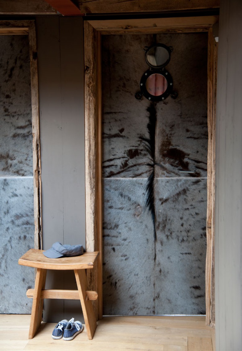 Pomysłowe drzwi z drewna i szarego futerka z metalowym okragłym okienkiem w korytarzu z szarymi ścianami (27680)