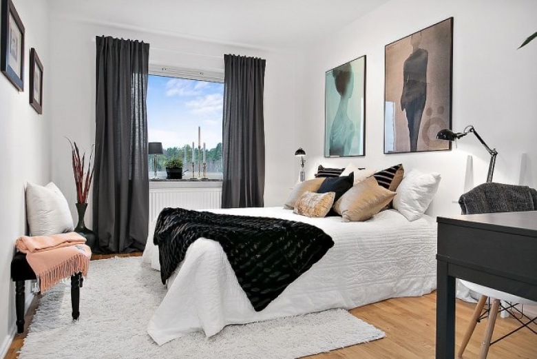 Nowoczesne artystyczne fotografie na ścianie w białej sypialni z czarnymi zasłonami,biurkiem i futrzaną narzutą (27519)