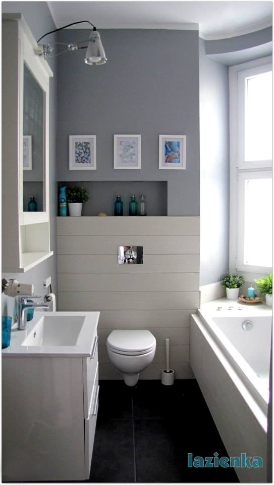 W prostej, biało-szarej łazience znajdują się pojedyncze, ale wpływające na charakter całości dodatki. Obrazki w...
