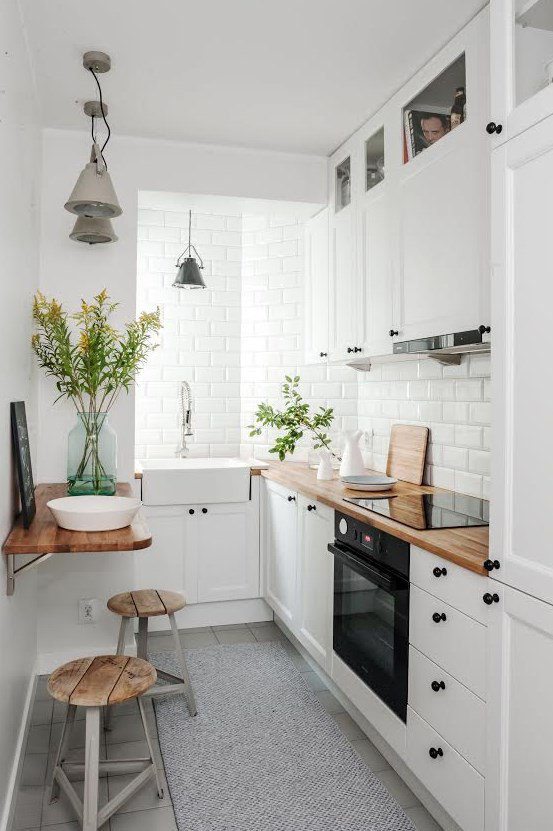 Mała kuchnia zaaranżowana w skandynawskim stylu, w całości w białym kolorze. Drewniane blaty i niektóre dodatki...