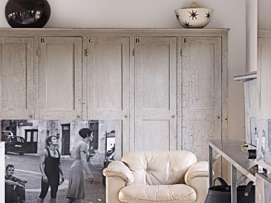 Deski vintage na suficie,zabudowa szaf z bielonego drewna,skórzany fotel kremowy,fotografia czarno-biała i metalowa konsolka w salonie (27393)