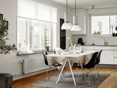 Biały skandynawski stół na kozłach,czarne nowoczesne krzesła na metalowych krzyżakach,szary tkany dywan,nowoczesne szklano-metalowe lampy nad stołem w białej kuchni (25828)