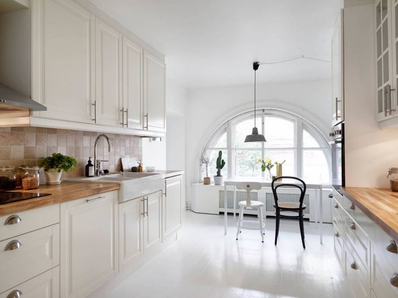 Biała kuchnia skandynawska z białą podłogą i półokrągłym oknem (26600)