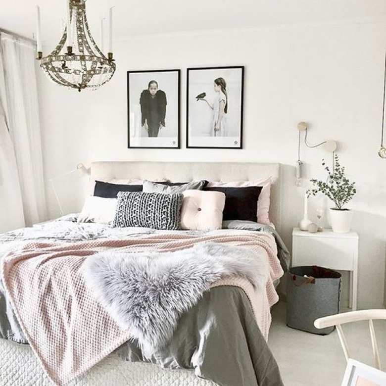Wystrój sypialni wzbogaca elegancki żyrandol, który zwraca na siebie uwagę. Czarne poduszki i ramki na ścianie na...