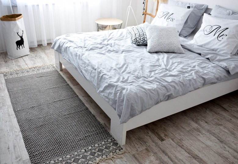 W aranżacji sypialni zastosowano rozmaite sposoby dekoracji. Jednym z nich jest cienki dywanik ułożony przed łóżkiem, który podobnie jak poduszki, ma lekko wzorzystą...