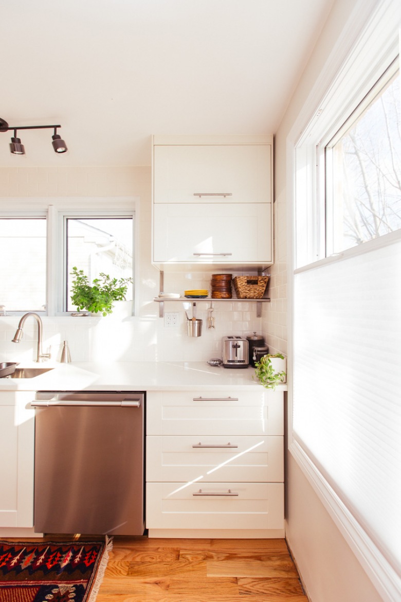 Niemal zupełnie białą kuchnię dodatkowo rozjaśniają duże okna, które zapewniają sporo naturalnego światła. Zwłaszcza w słoneczny dzień pomieszczenie wiele zyskuje, a wystrój wydaje się pogodny i tworzy przyjazny klimat. Wzorzysty dywanik na podłodze zdecydowanie dekoruje...