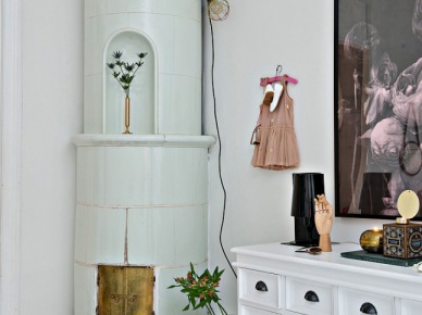 Okrągły ceramiczny piec skandynawski, biała komoda z szufladkami i nowoczesna grafika na ścianie w salonie (28414)