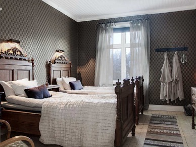 Stylowe rzeźbione łóżka z drewna w skandynawskiej sypialni z podłogą z surowych desek i tkanym dywanikiem (27639)