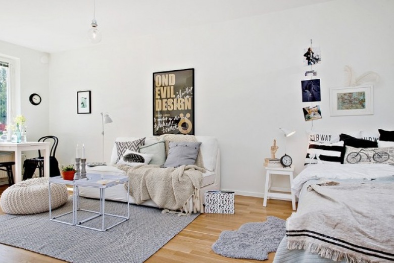 Czarno-białe poduszki na łóku stojącym w salonie z białymi stolikami,białą sofą i szarym dywanem (24697)