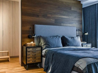 Drewniana ściana i szare łóżko z materiałowym wezgłowiem w sypialni (56074)