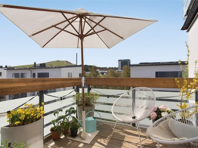 Białe ażurowe fotele, parasol i drewniany podest  w aranżacji małego balkonu (23409)