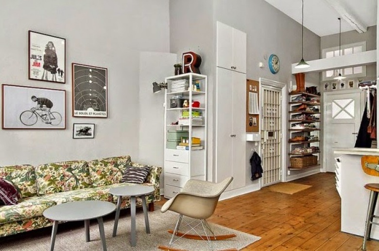 Wiszące półki, gabloty,szare stoliki,krzesła na płozach i zielona wzorzysta sofa w salonie (26380)