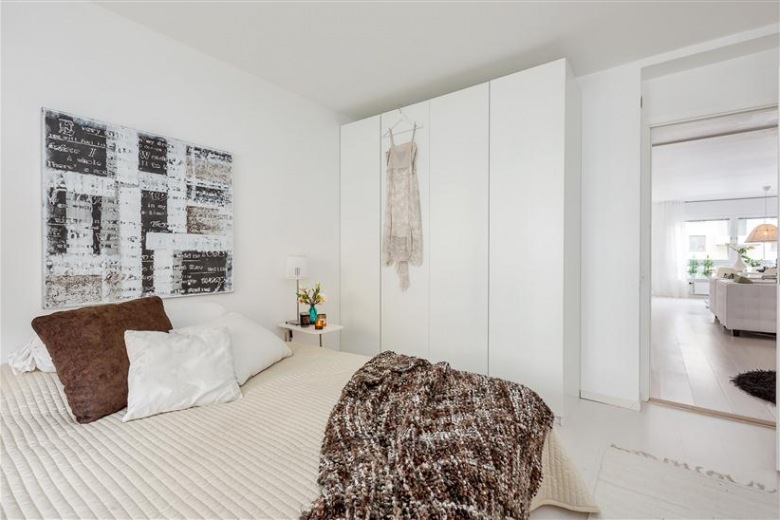 Biała szafa,nowoczesny obraza,brązowa poduszka i beżowa narzuta na łóżko (22442)