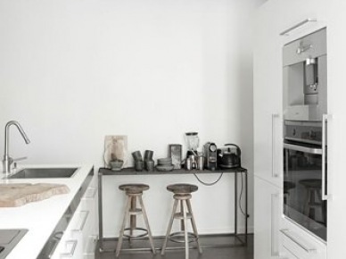 Betonowa posadzka, drewniane stołki i industrialna konsolka w białej kuchni (21149)