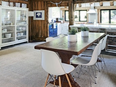 Drewniany wiejski stół,białe nowoczesne krzesła,przeszklona witryna i  deski na ścianach w  wiejskiej  kuchni z jadalnią (22873)