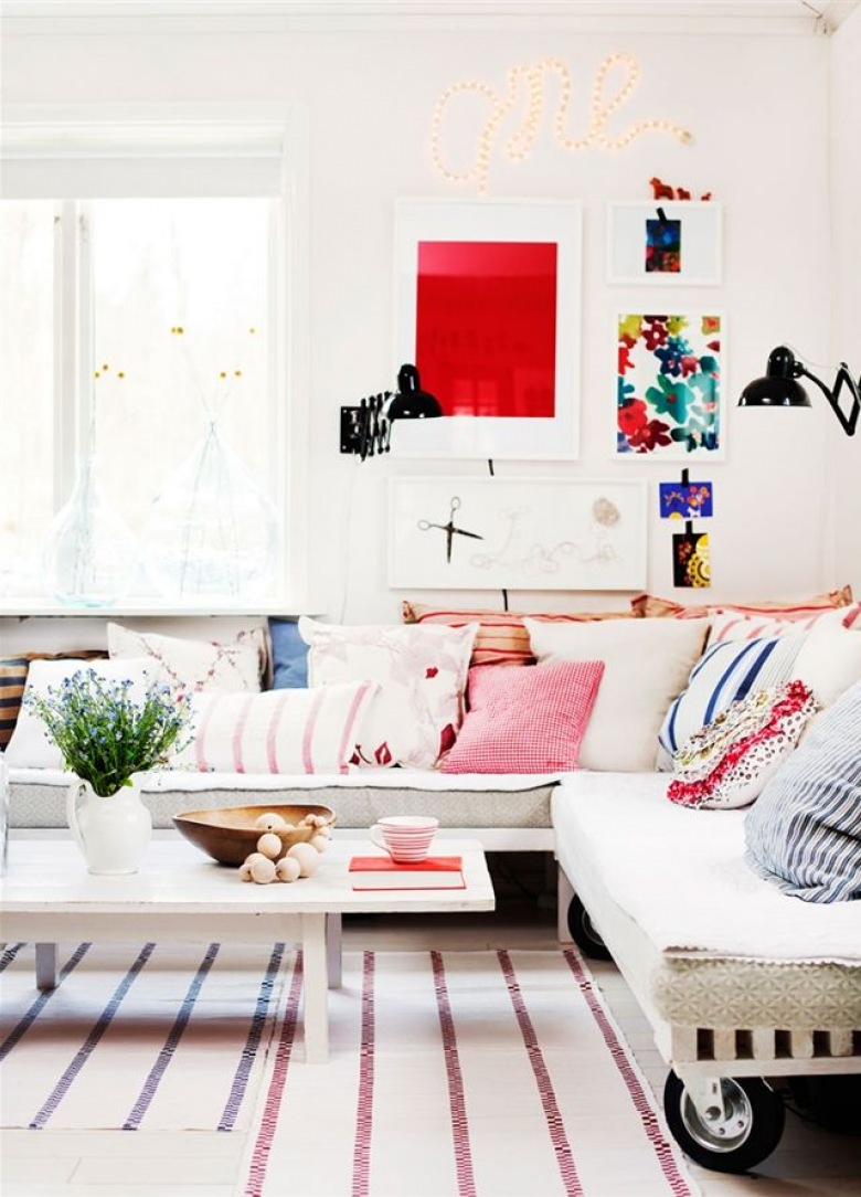 Czerwone, różowe i niebieskie poduszki dekoracyjne na sofie i kolorowe plakaty na ścianie (28056)